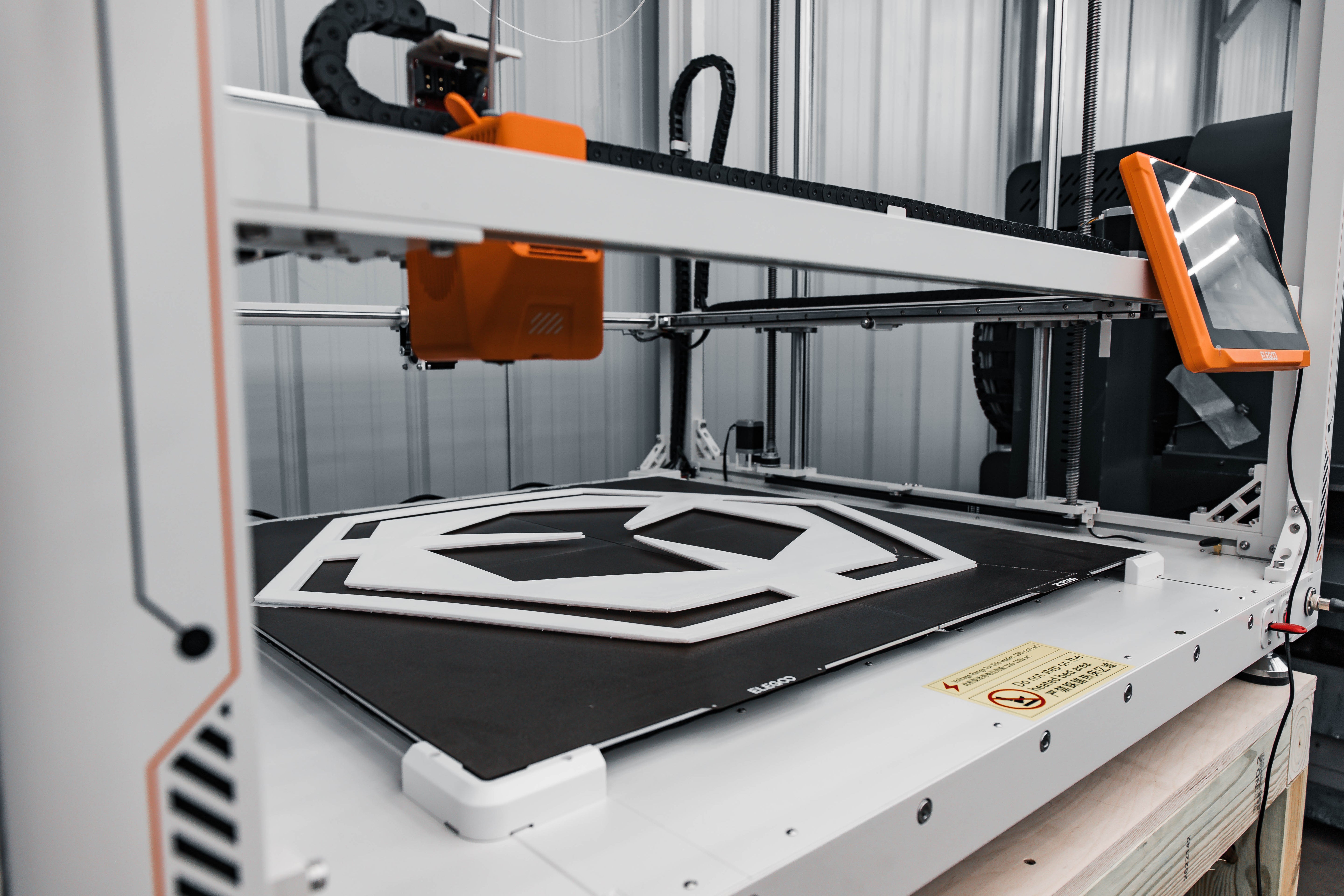 3D printer in operation with a white Spark Robotic logo on its platform.