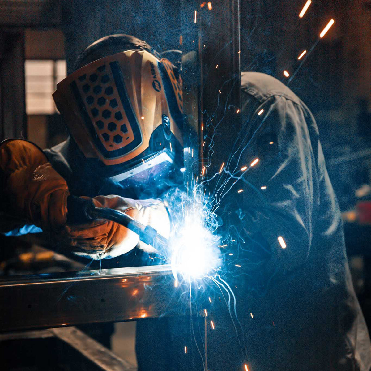 Person welding with sparks flying in a workshop setting