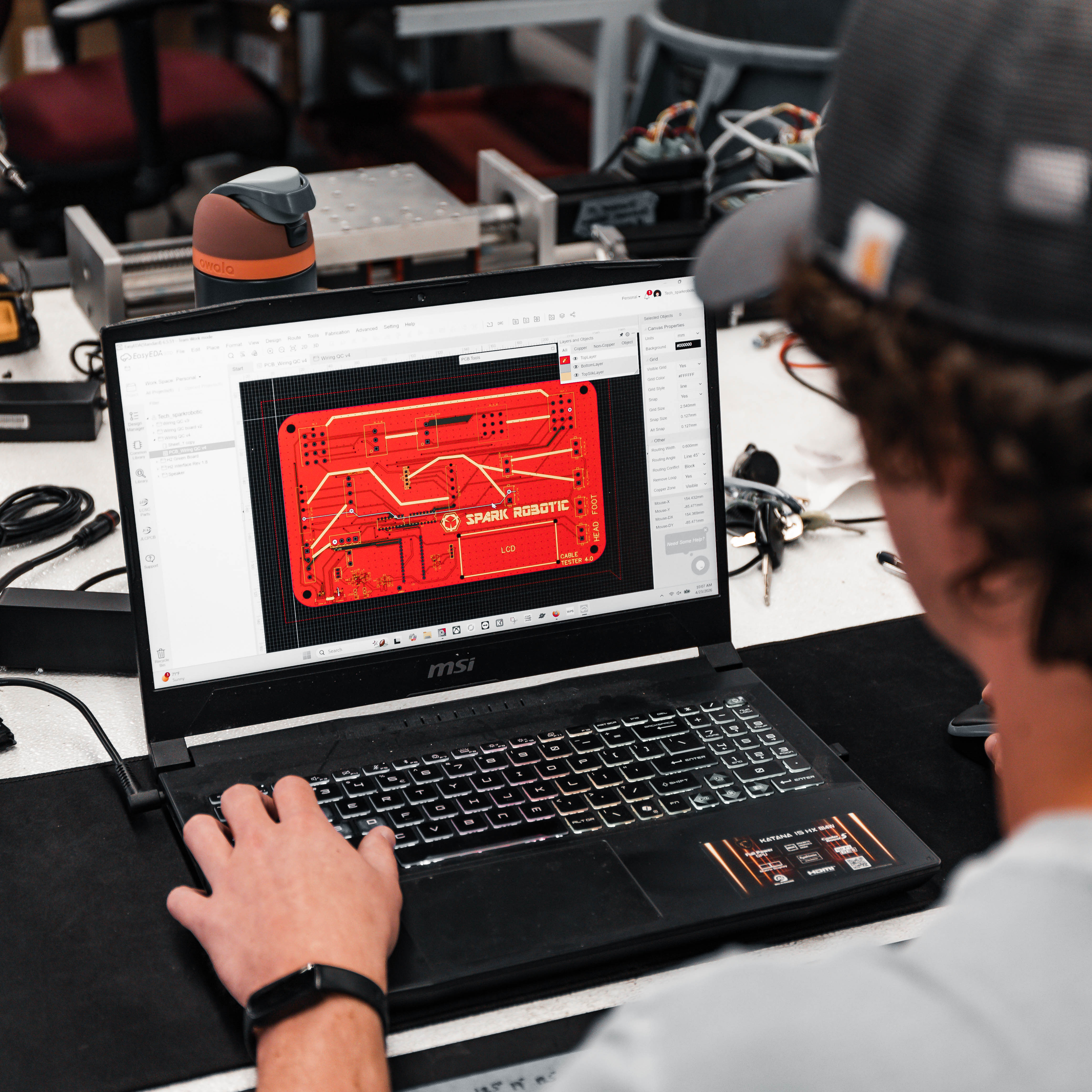 Person working on a laptop with a technical diagram on the screen in a workshop setting