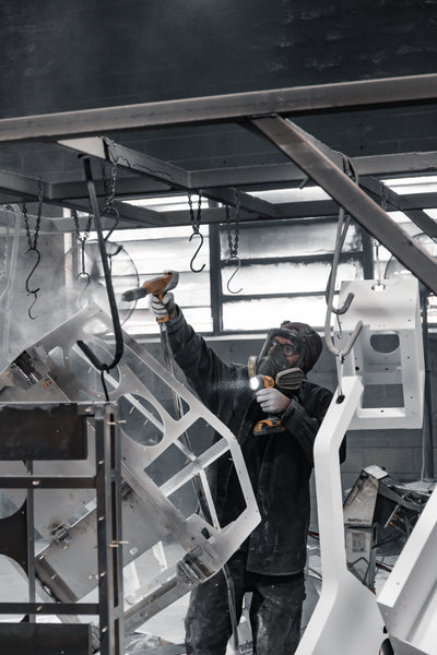 Person powder coating a large metal structure in a workshop