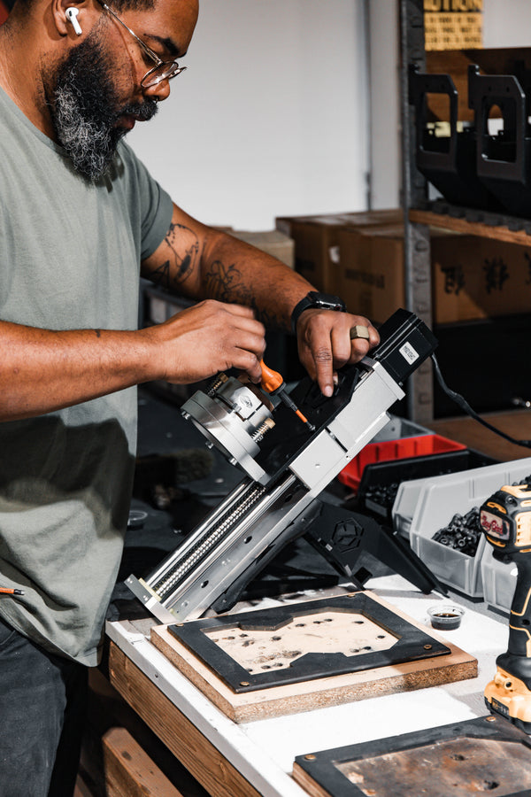 Man using a power tool on a wooden surface in a workshop setting