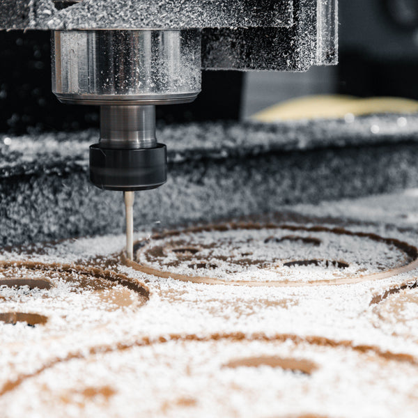 CNC router machine cutting a piece of acrylic with dust around it