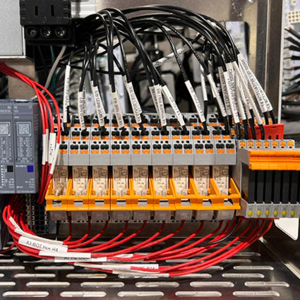 Wiring harness with labeled wires connected to a junction box in an industrial setting.