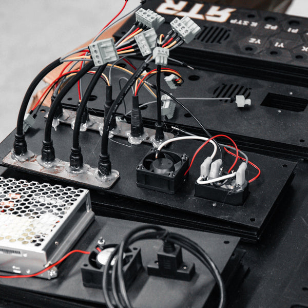 Close-up of electronic components and wiring on a black board with visible text in the background.