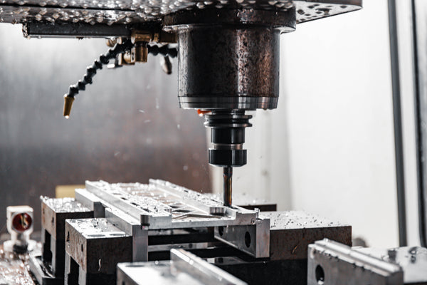 CNC machine in operation with metal parts on a worktable.