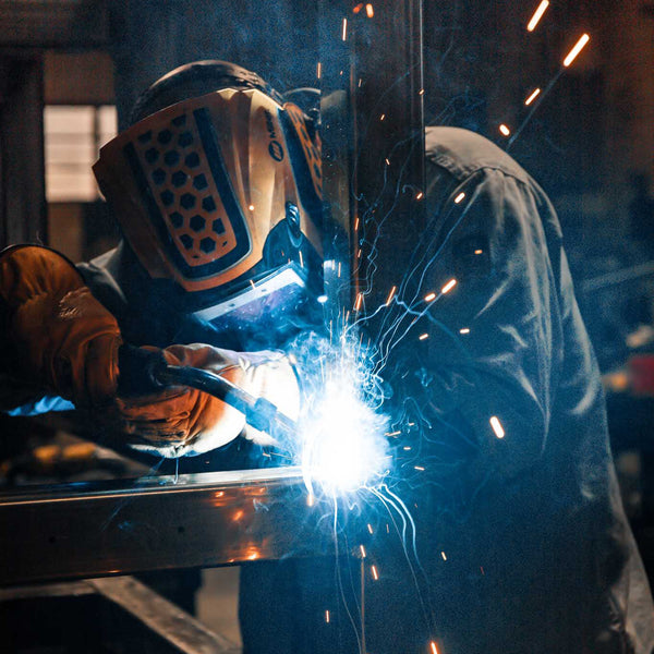 Person welding with sparks flying in a workshop setting