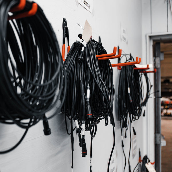 Cables and tools hanging on a wall-mounted organizer in a workshop setting.